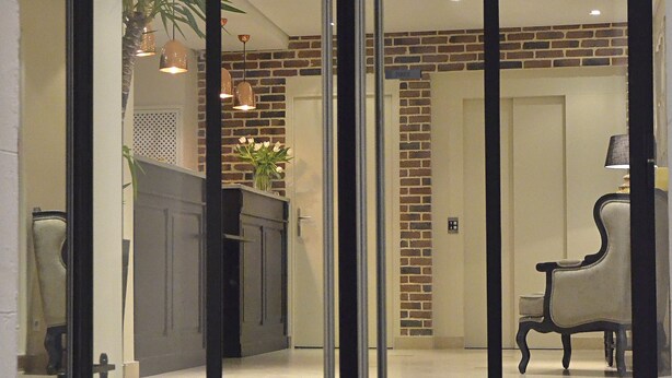 A room with a large sliding glass door, a brick wall, and a bench. - Hotel Le Fer à Cheval (Trouville-sur-Mer)