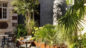 A patio with a table and chairs, surrounded by various plants and a brick wall. - Hotel Le Fer à Cheval (Trouville-sur-Mer)