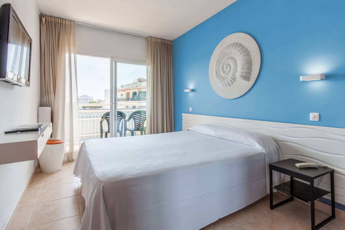 Ein Hotelzimmer mit Bett, Schreibtisch, Stuhl, Fernseher und einem Balkon mit Blick.