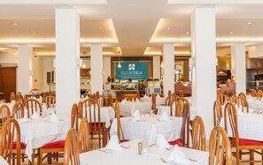 Hotellin ruokailutilassa on useita pöytiä ja tuoleja, keskeisellä paikalla sijaitseva buffetpöytä sekä kyltti, jossa lukee: ”BluSea Hotel Montevista Hawaii”.