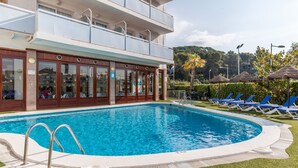 A hotel with a swimming pool, lounge chairs, and a building with multiple floors. - BLUESEA Montevista Hawai (Lloret de Mar)