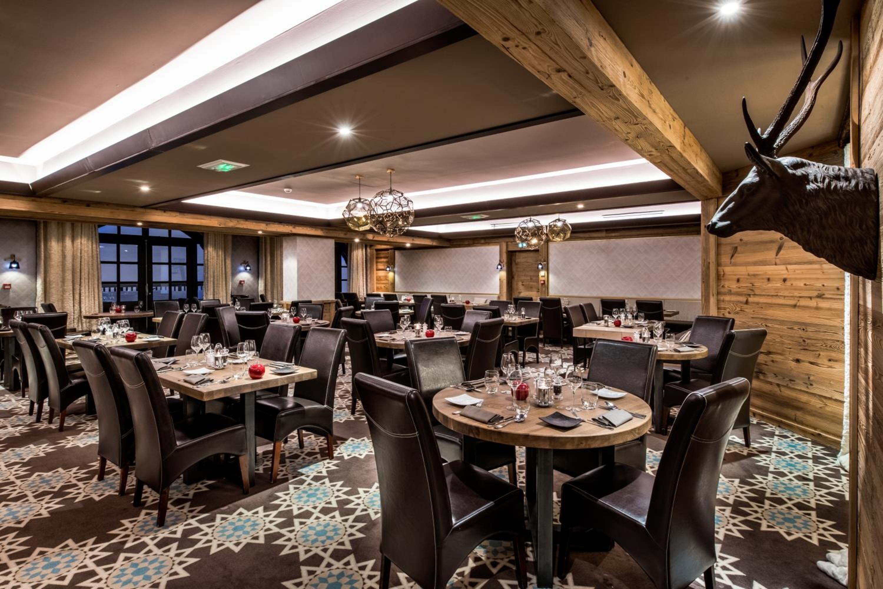 A restaurant with round tables, black leather chairs, and a patterned carpet.