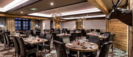 A restaurant with round tables, black leather chairs, and a patterned carpet.