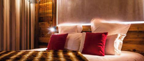 A bed with white and red pillows, a fur throw, and a wooden headboard.