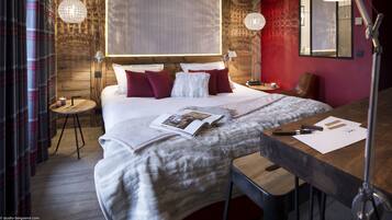 A modern bedroom with a large bed, a wooden headboard, a desk, and a chair.