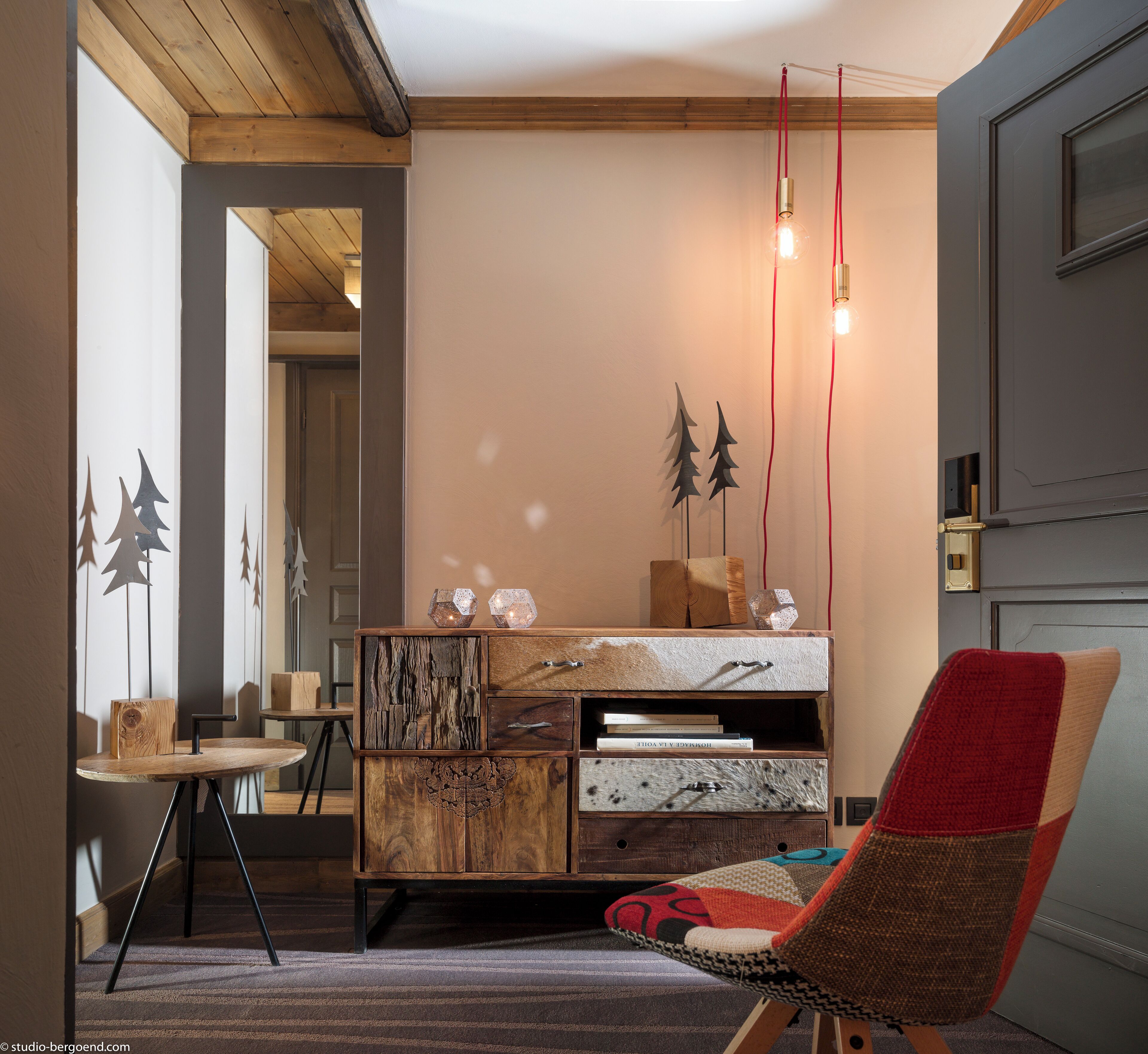 A cozy room with a wooden cabinet, a red and beige chair, and a desk with a lamp.