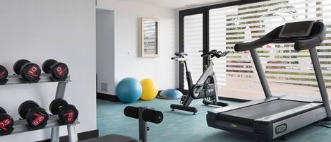 Un gimnasio con equipo de ejercicio, incluyendo mancuernas, una banca y una cinta de correr.