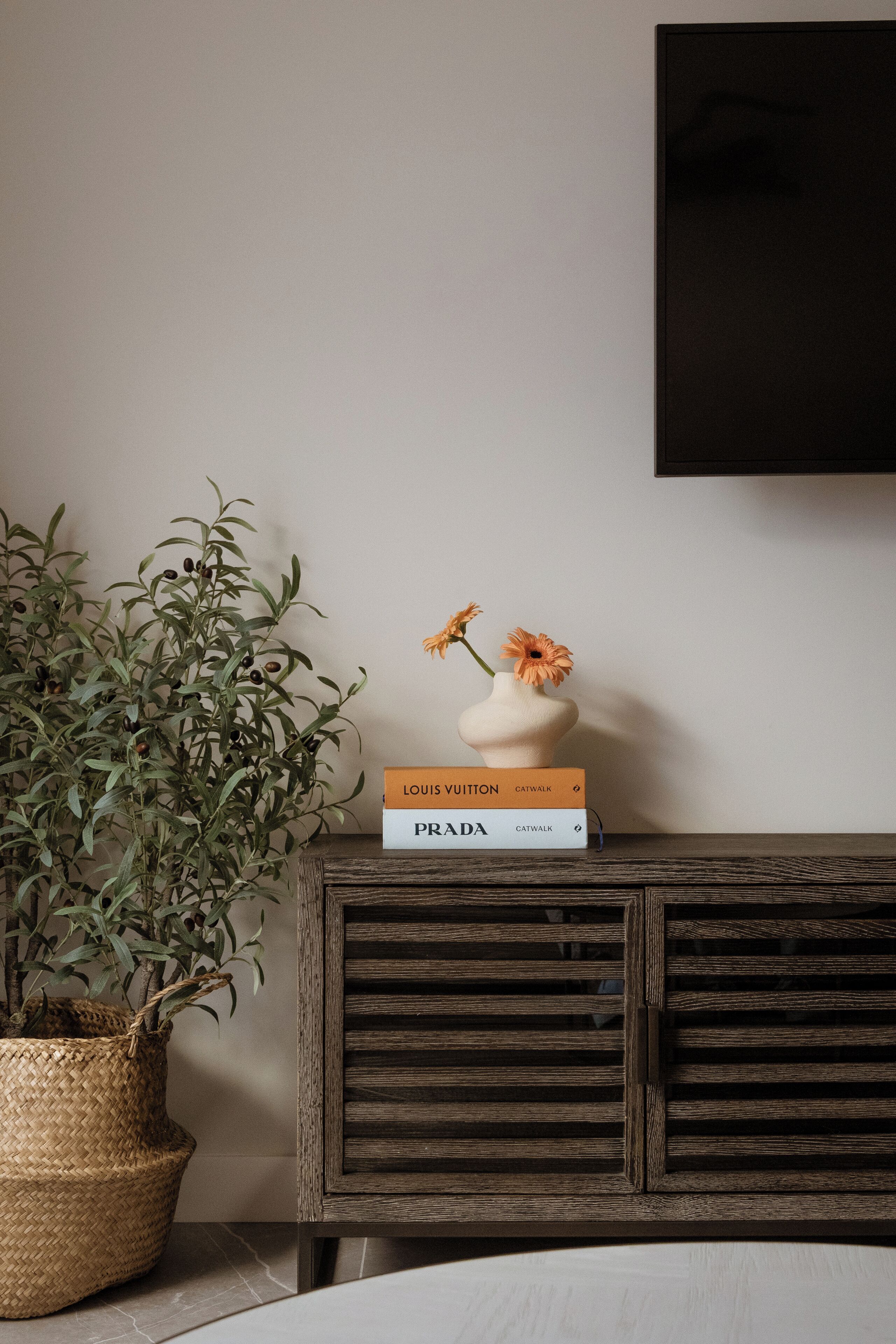 A wooden cabinet with a vase of flowers and two books on top.