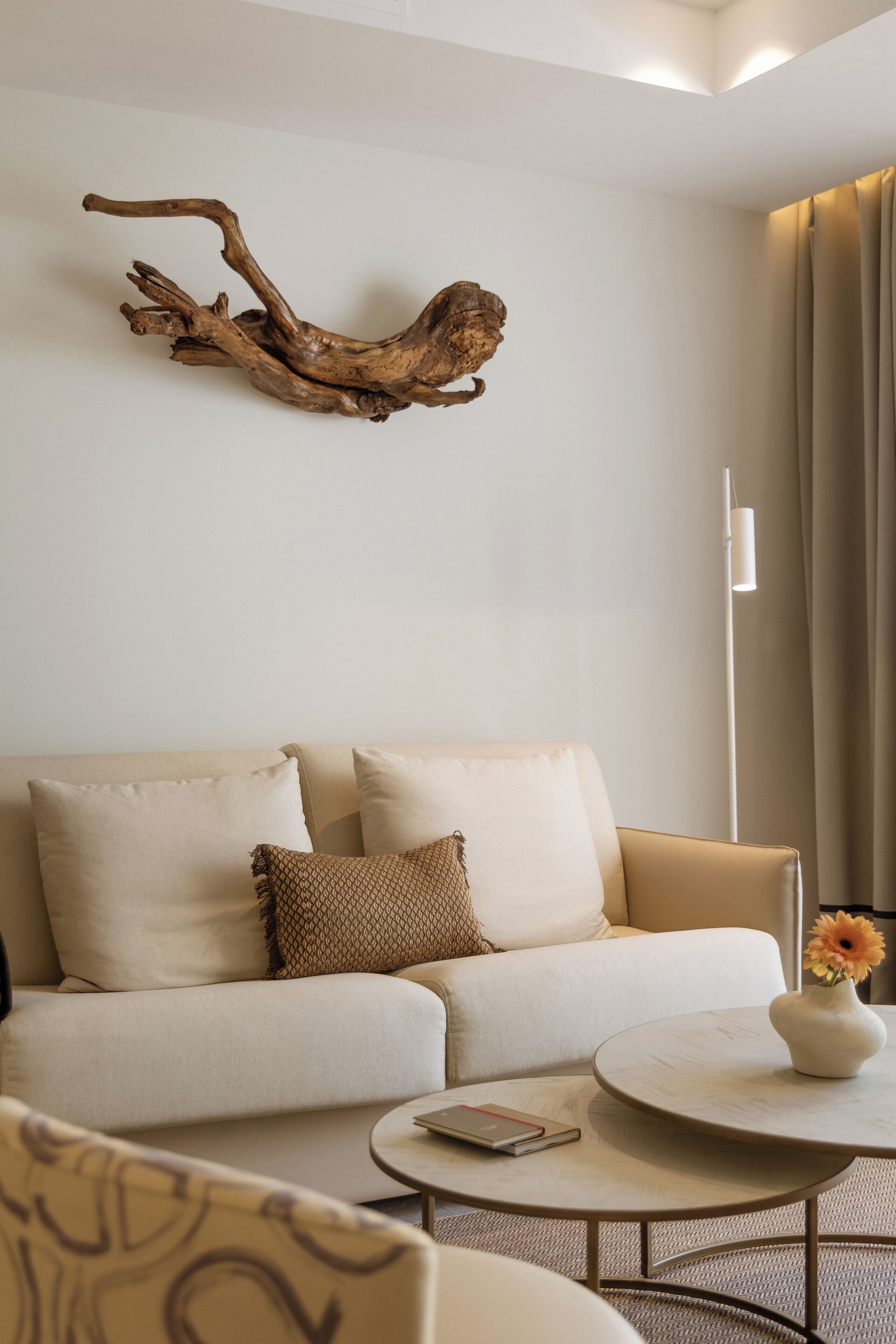 Una sala moderna con un sofá, una mesita de centro y un elemento decorativo de madera en la pared.