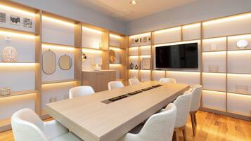 A modern conference room with a long table, white chairs, and illuminated wall panels.