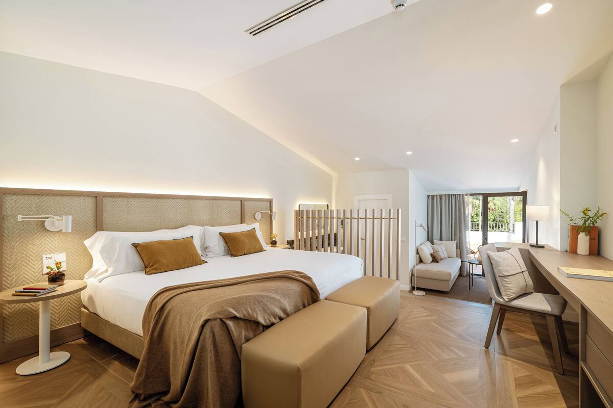 A modern hotel room with a large bed, a seating area, and a desk.