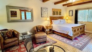 A bedroom with a wooden bed, a nightstand, a chair, a table, and a ceiling fan. - Blue Iguana Inn (Ojai)