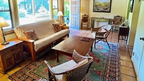 A cozy living room with a wooden ceiling, a sofa, a coffee table, wicker chairs, and a patterned rug. - Blue Iguana Inn (Ojai)