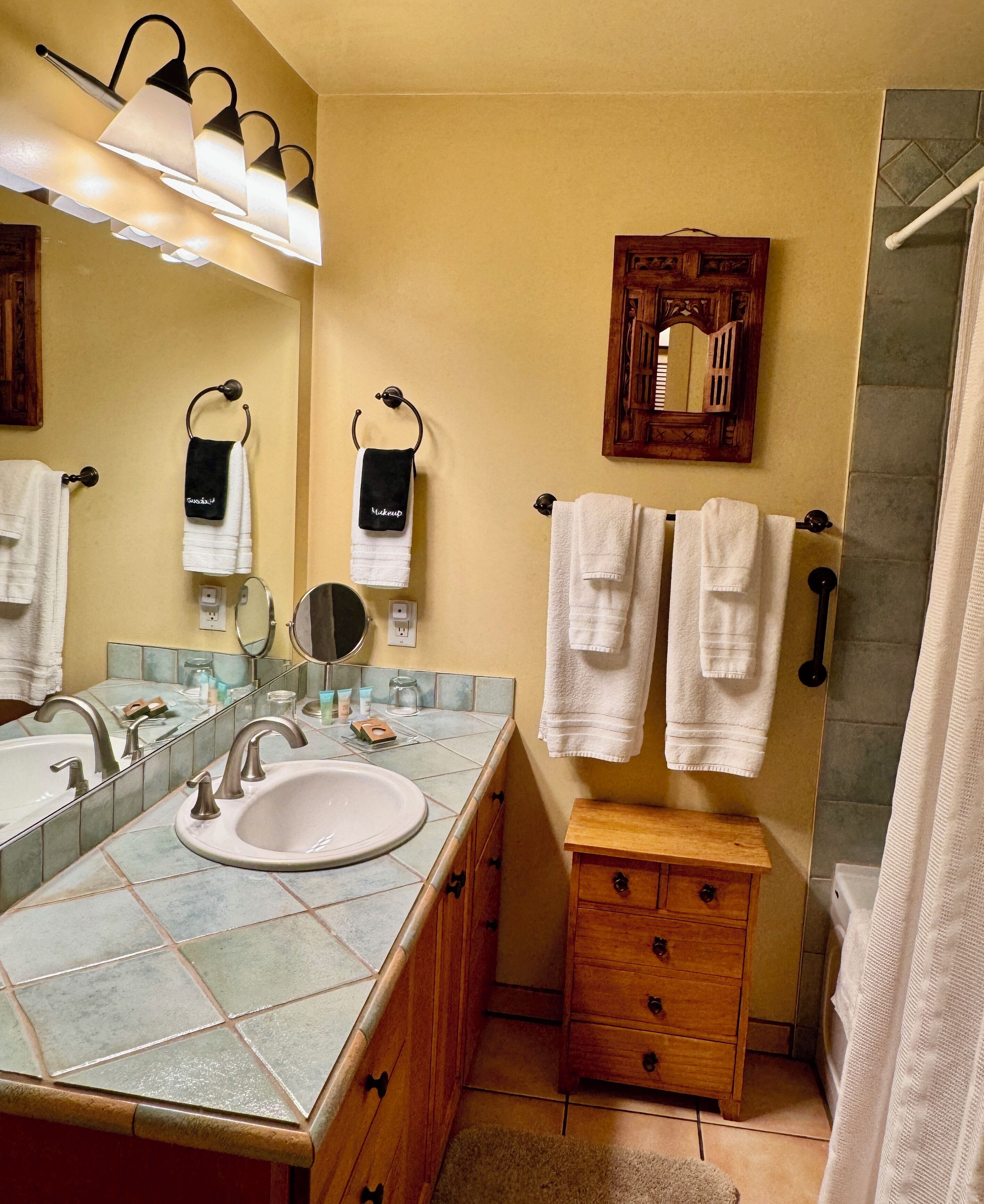 A bathroom with a large sink, two mirrors, a wooden cabinet, and a shower area.