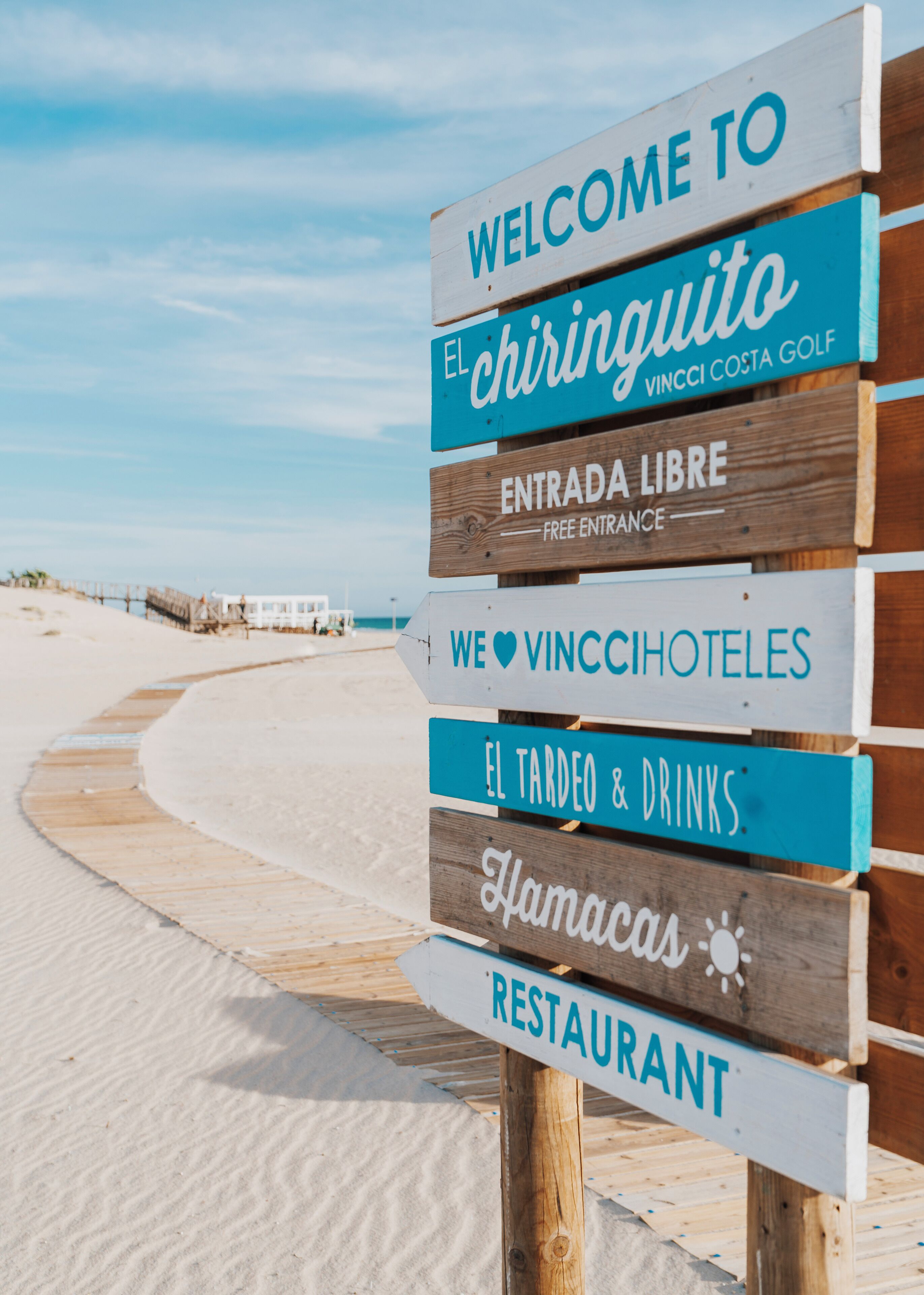 Un panneau en bois, divisé en plusieurs sections, indiquant les différents services disponibles, tels qu’une entrée gratuite, un restaurant et un bar.