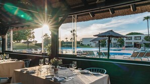 Un restaurante con una mesa lista para comer, con vistas a una piscina y un edificio.