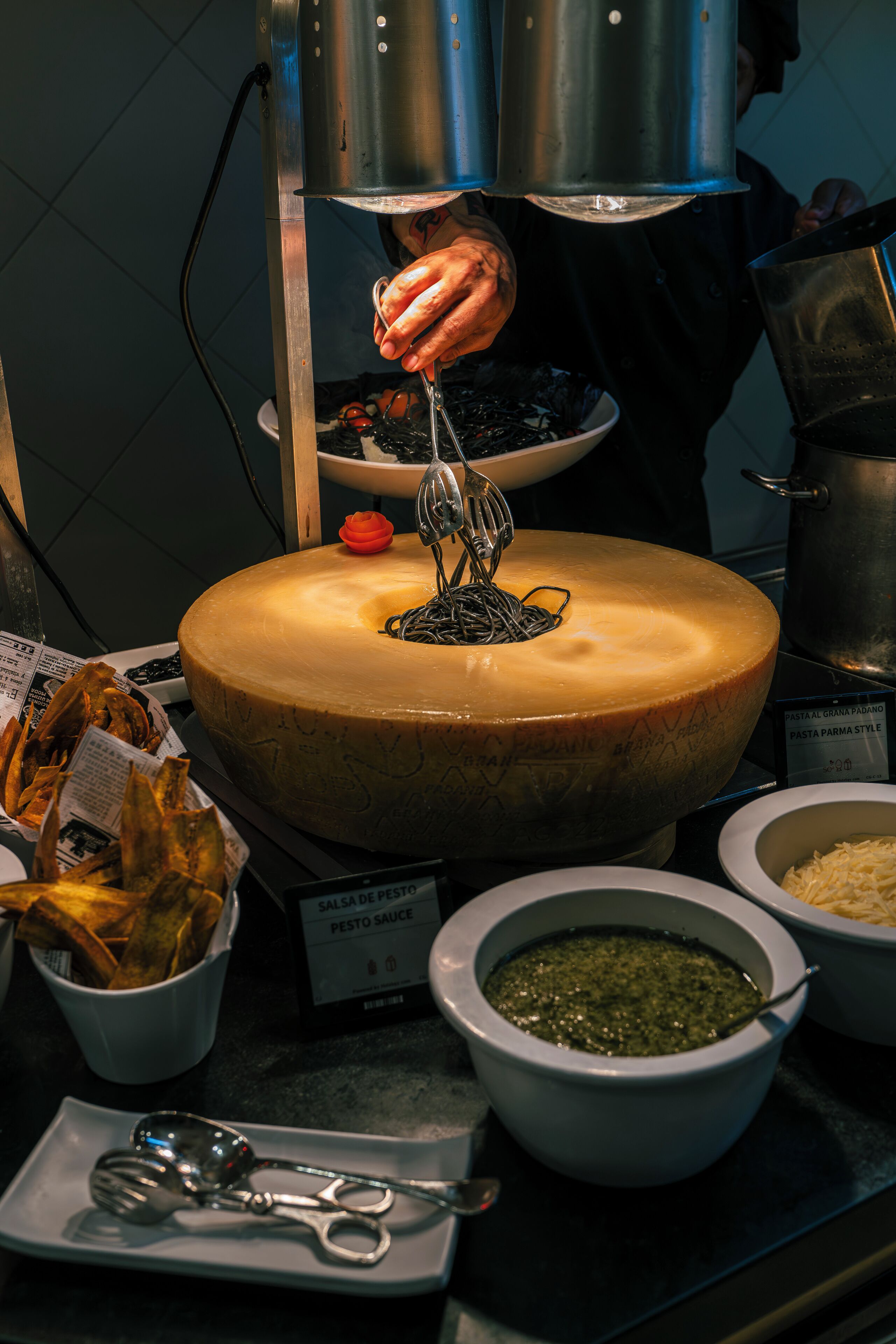 A cheese wheel with a cheese slicer above it, surrounded by various food items and condiments.
