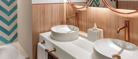 Un baño moderno con dos lavamanos, un espejo grande y una bañera.
