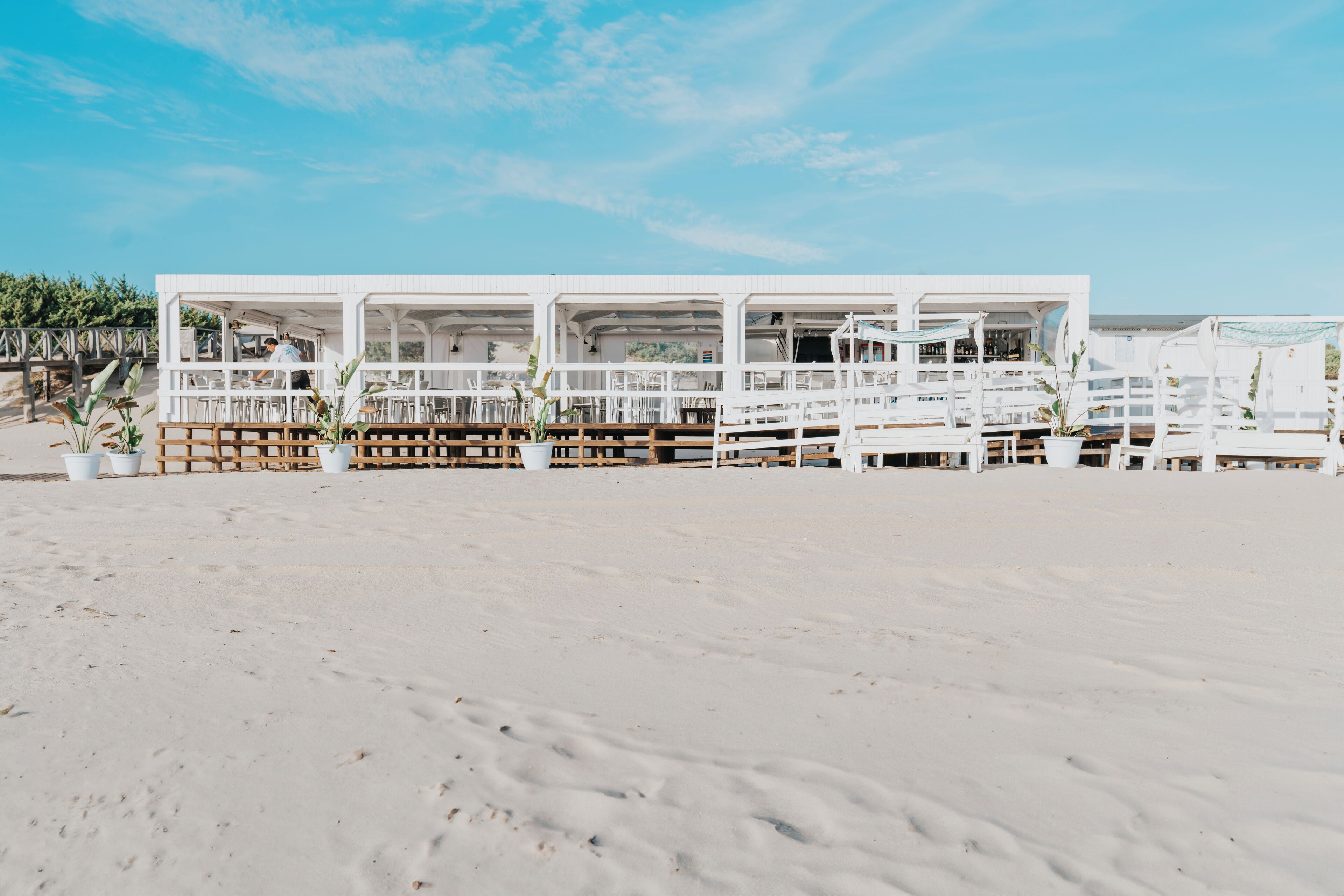 A beachfront building with multiple balconies, a sandy beach in the foreground, and a clear sky.