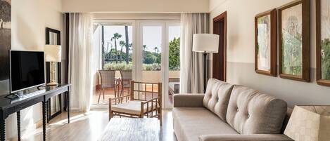 Una sala de estar moderna con sofá, televisor, mesa de centro y balcón con vistas a palmeras.