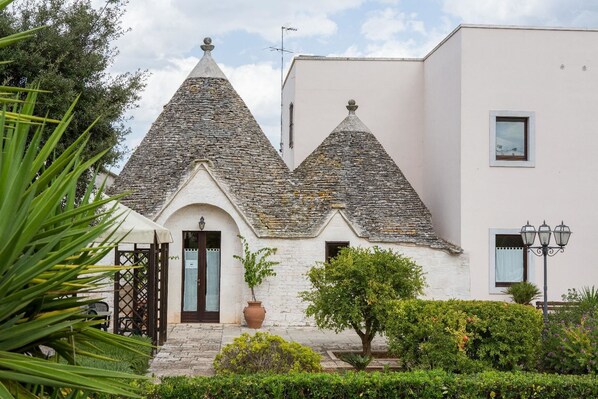 A building with a stone roof and a white facade. - Hotel Ramapendula (Alberobello)