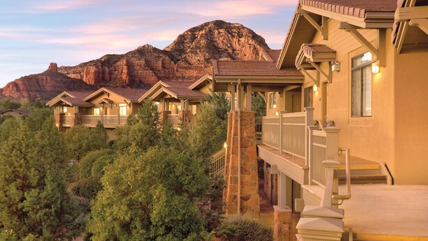 A resort with multiple guest rooms, a stone staircase, and a mountain backdrop.
