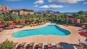A resort pool area with lounge chairs and a view of mountains.