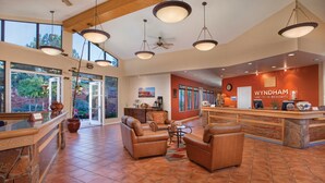 A spacious lobby with leather seating, a reception desk, and large windows offering views of the outdoors.