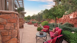An outdoor patio area with stone walls, red outdoor furniture, and potted plants.
