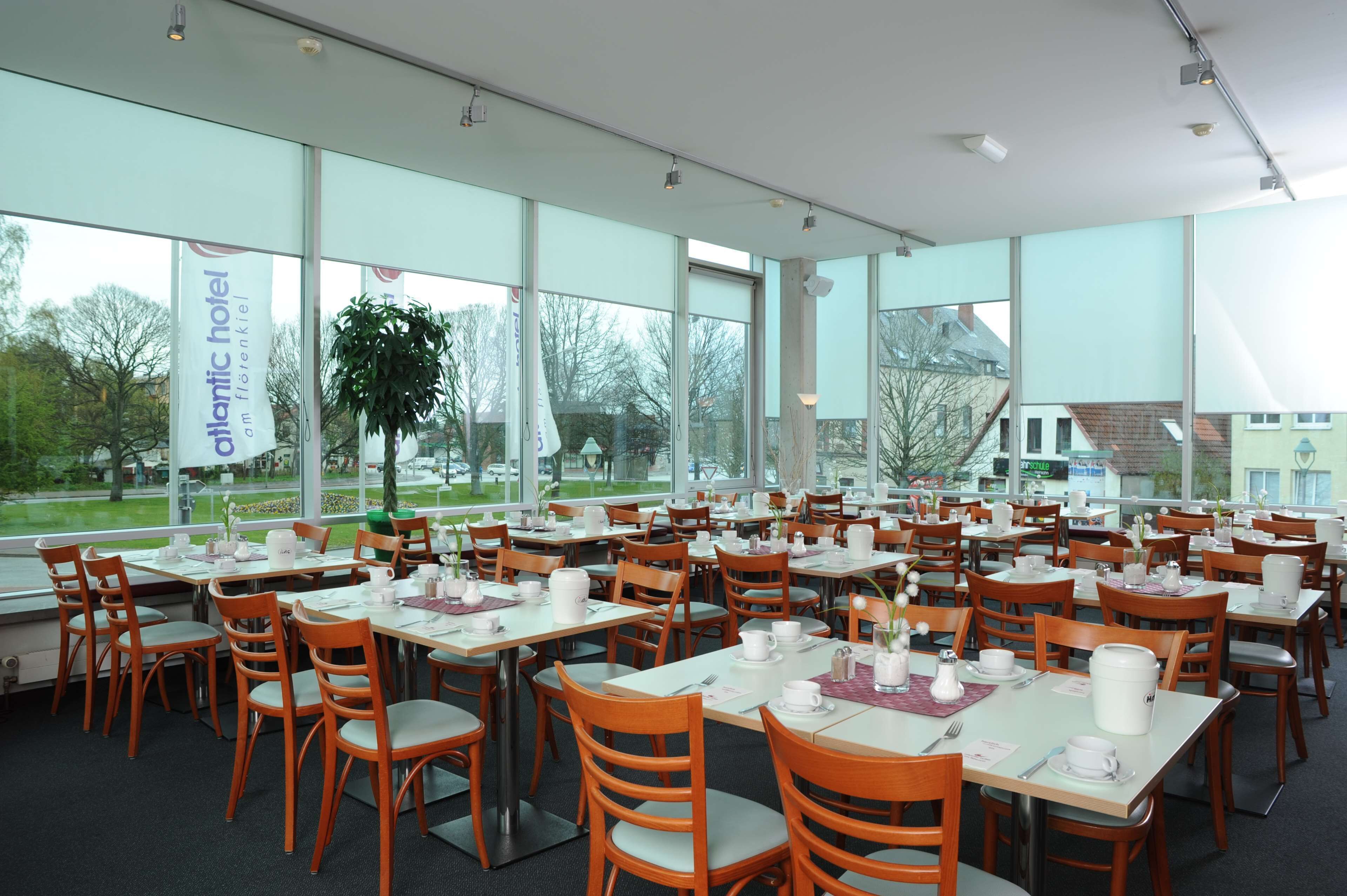 A spacious indoor dining area with large windows, wooden tables, and chairs.