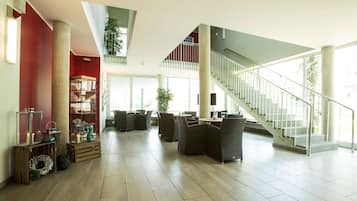 A spacious lobby with a staircase, a high ceiling, and a large window providing natural light.