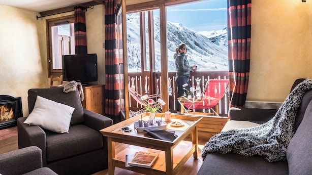 A cozy living room with a fireplace, a television, and a view of a snowy mountain. - Résidences Village Montana by Les Etincelles  (Tignes)