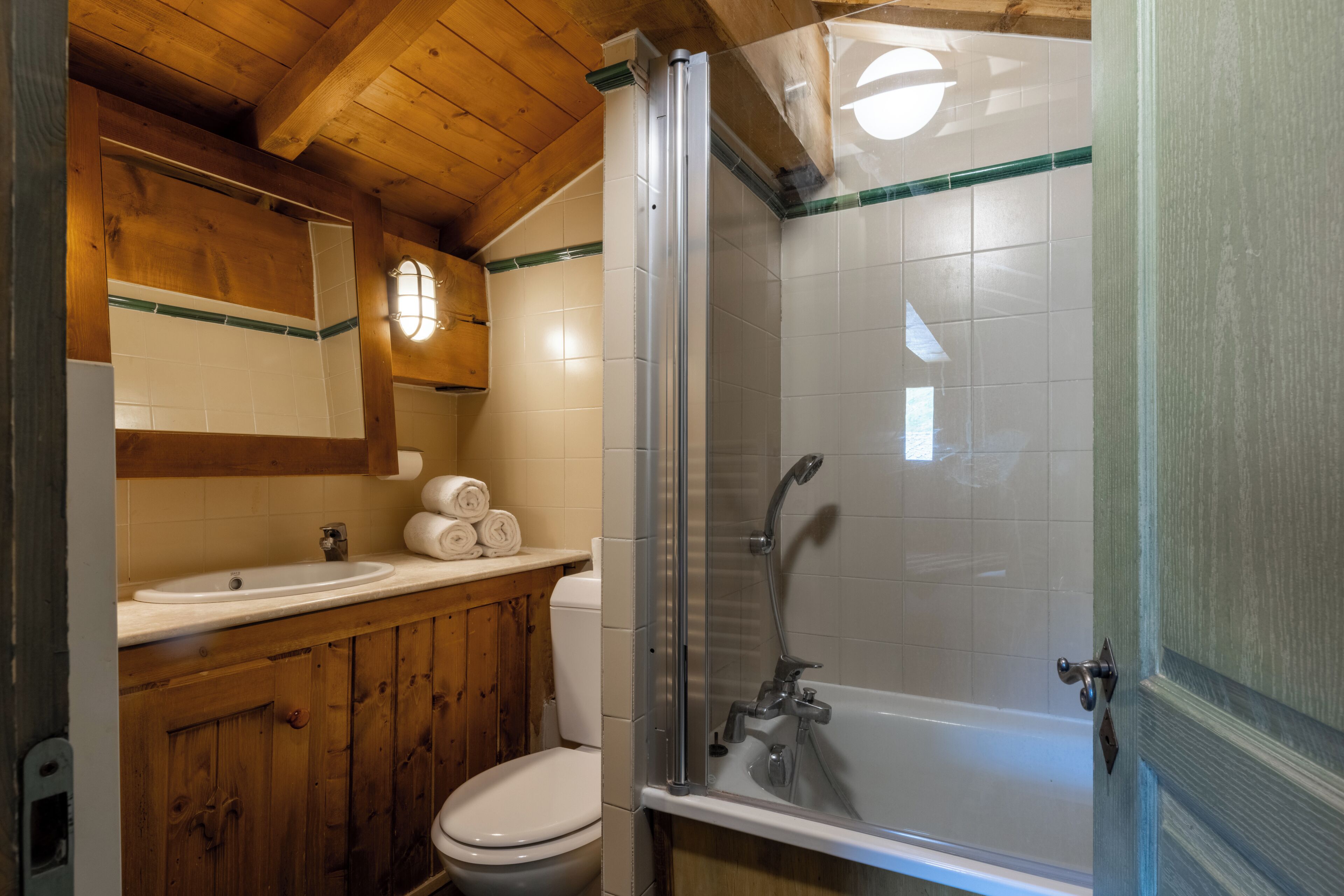 A bathroom with a wooden vanity, a toilet, a sink, and a glass-enclosed shower.