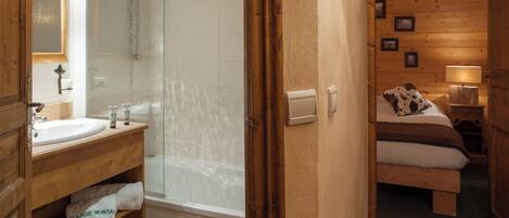 A wooden bathroom with a sink, mirror, and shower.