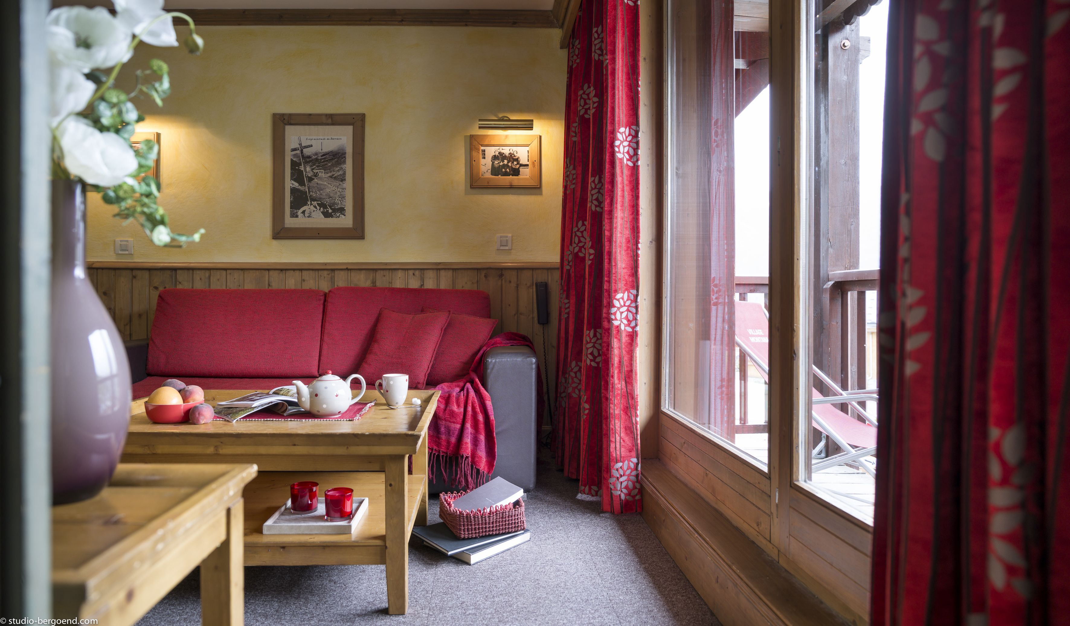 A cozy room with a wooden bench, a table with a teapot, cups, and a basket of books.