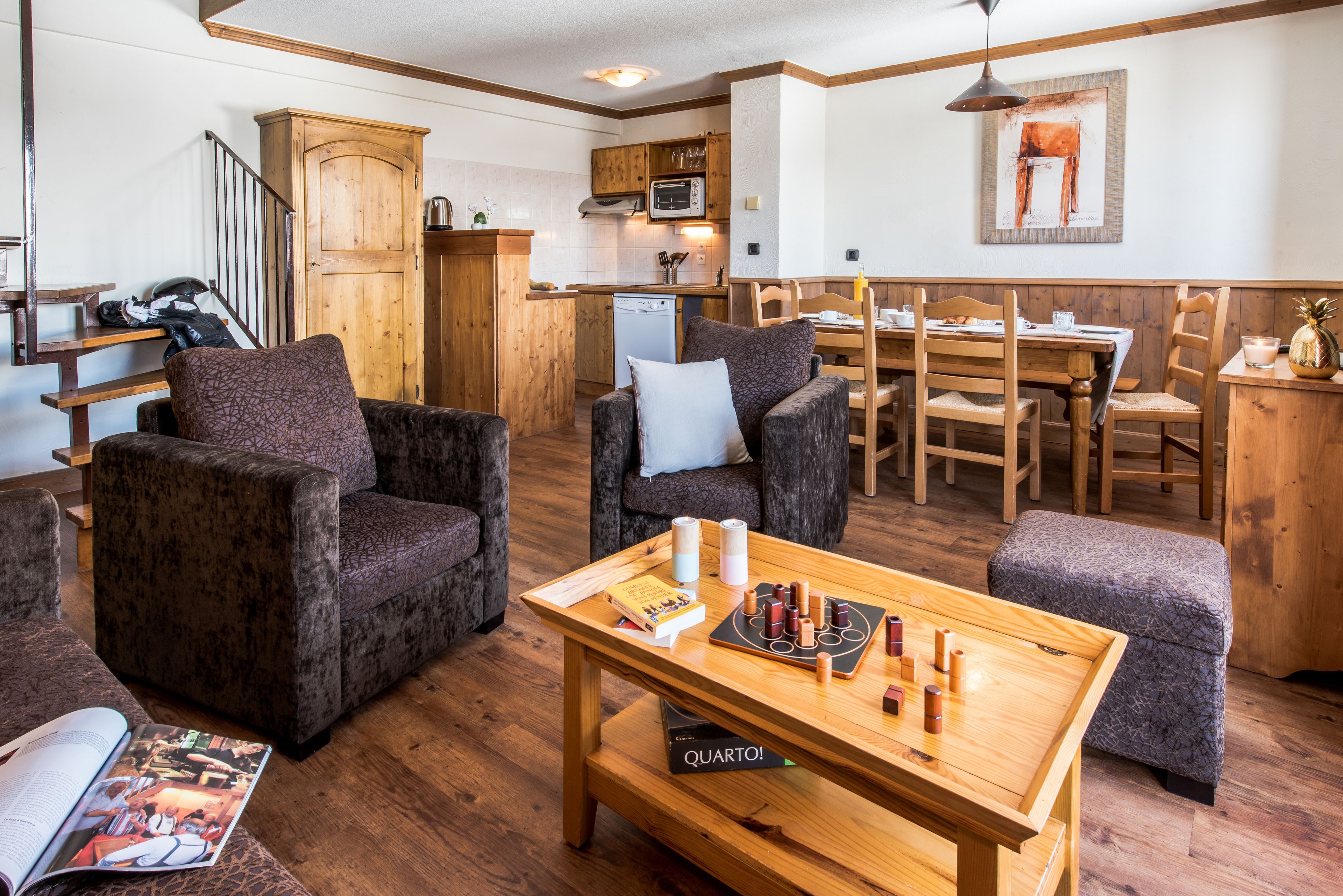 Un salon chaleureux avec une table basse en bois, des sièges confortables, une cuisine dotée de meubles en bois et une table à manger.