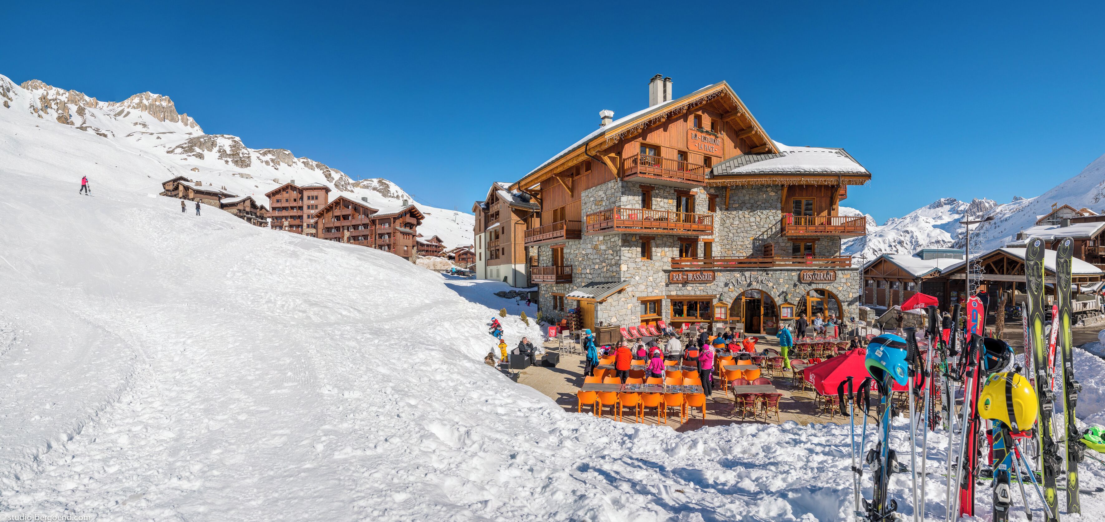 A ski resort with a stone building and wooden balconies, surrounded by snow-covered mountains.