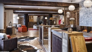 A spacious lobby with a fireplace, wooden accents, and a cowhide rug. - Résidences Village Montana by Les Etincelles  (Tignes)