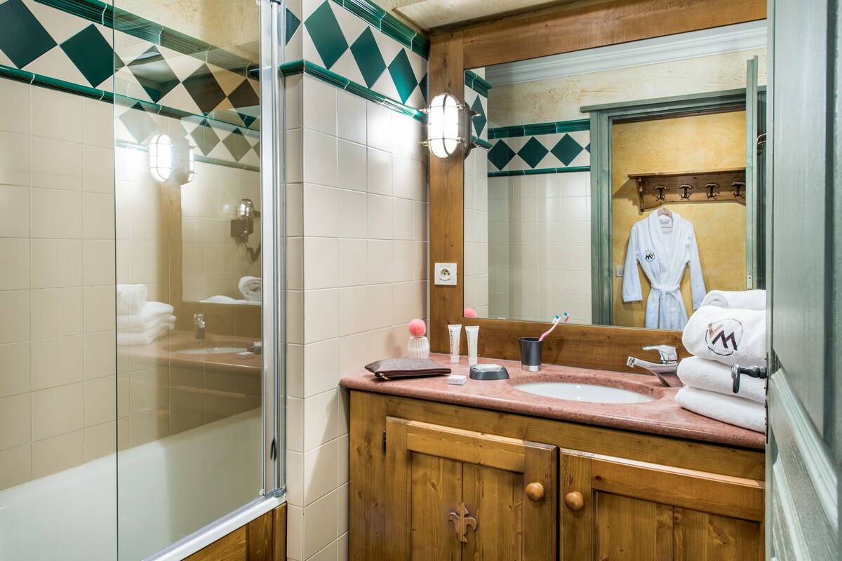 A bathroom with a glass shower enclosure, a wooden vanity with a sink, and a mirror above the vanity.