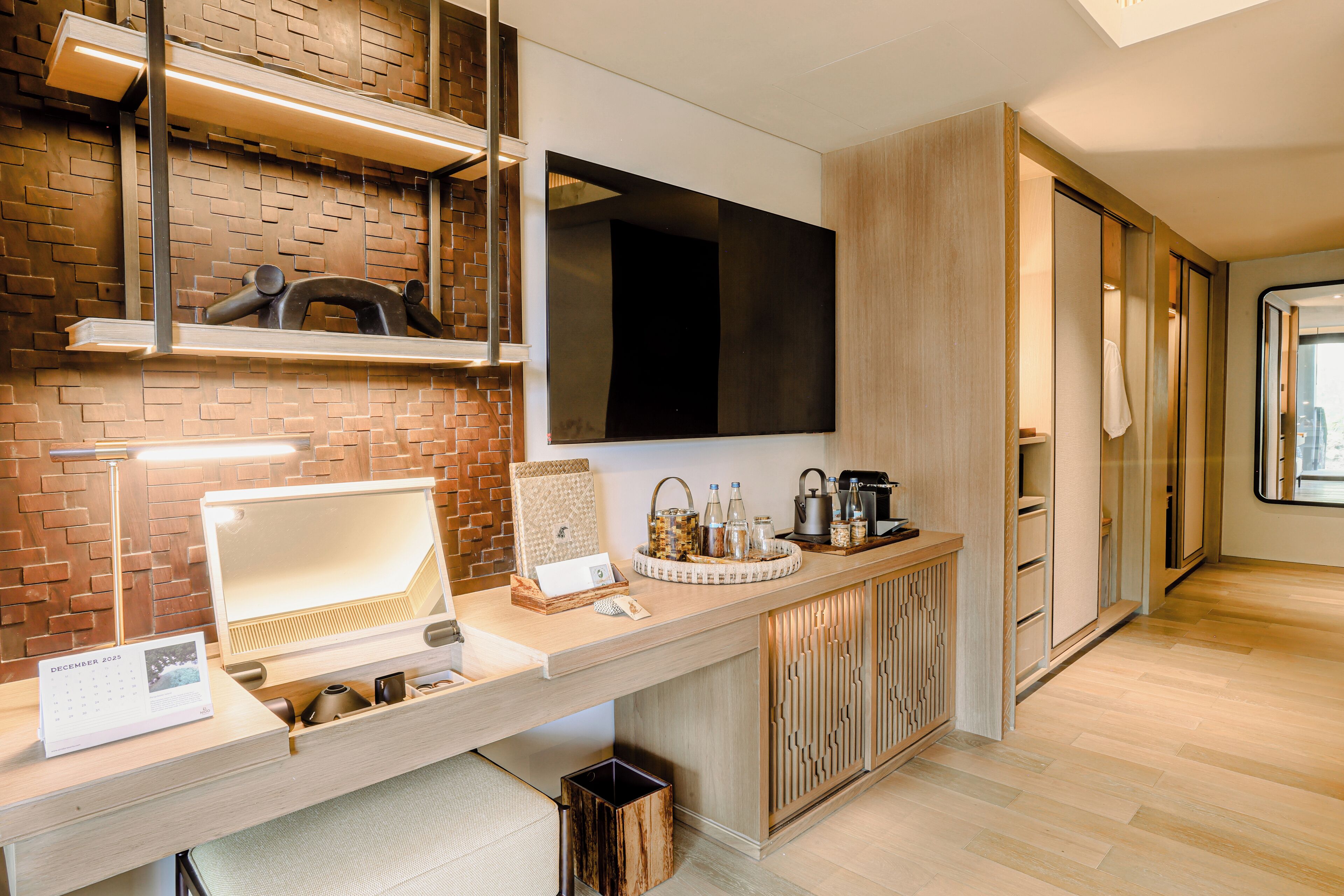 A modern kitchen with a brick wall, a flat-screen TV, and a wooden counter with various items.