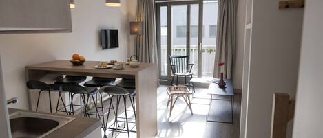Una cocina moderna con barra, una mesa de comedor con sillas y vista al balcón.