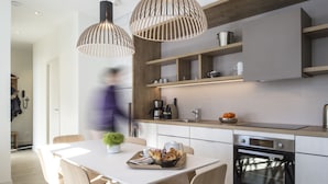 A modern kitchen with wooden cabinets, a built-in oven, and pendant lights. - Appart'Hôtel le Génépy (Chamonix-Mont-Blanc)