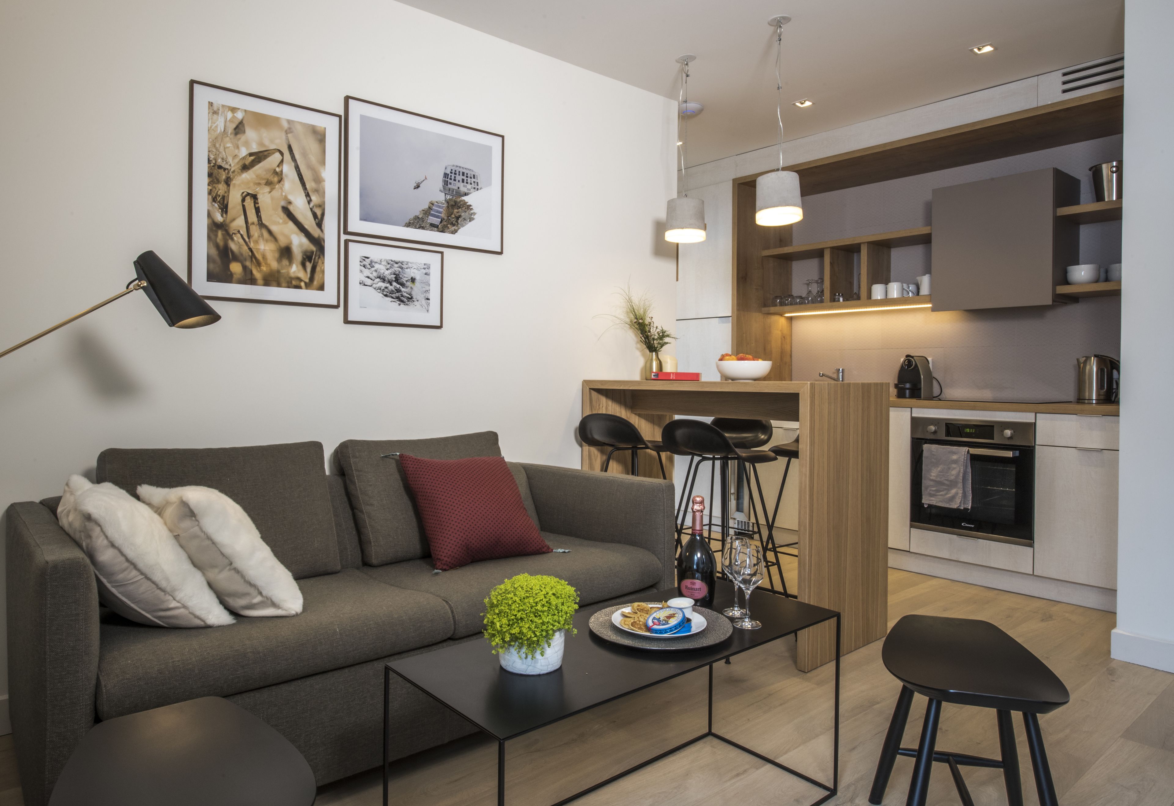 A modern living room with a sofa, coffee table, and a small kitchen area with a dining set.