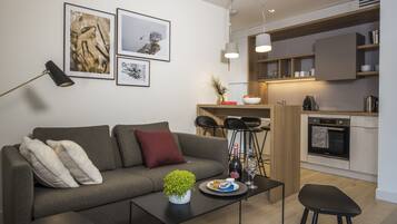 A modern living room with a sofa, coffee table, and a small kitchen area with a dining set.
