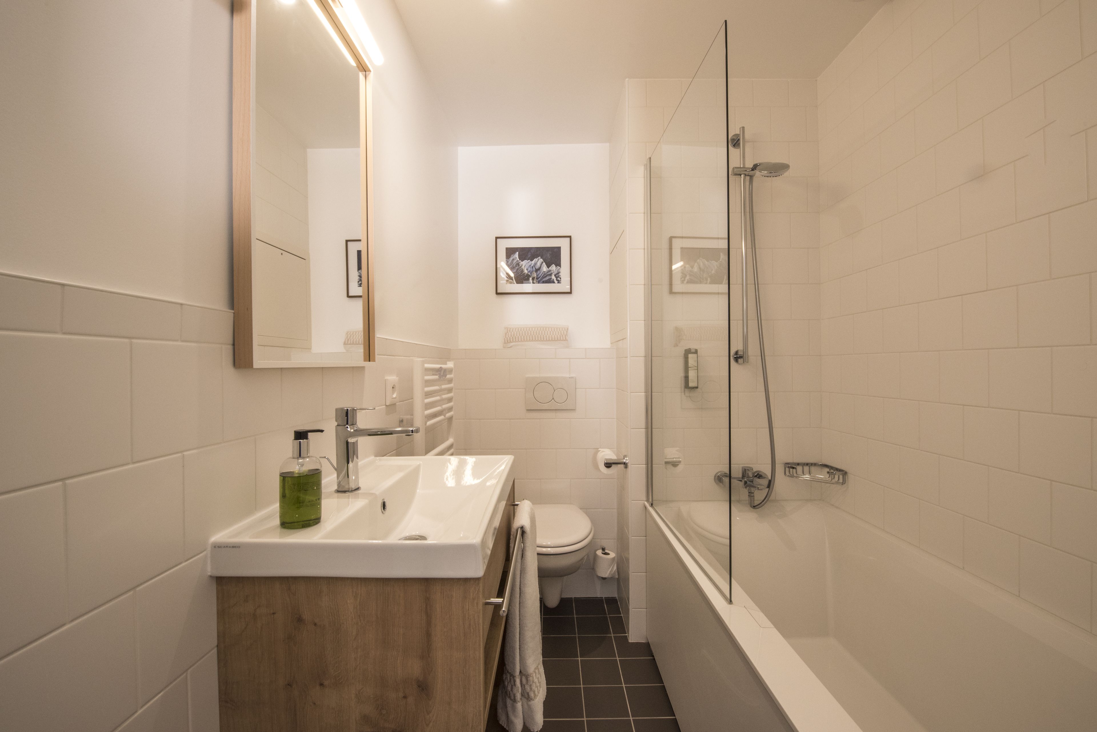 A modern bathroom with a wooden vanity, a glass shower enclosure, and a toilet.