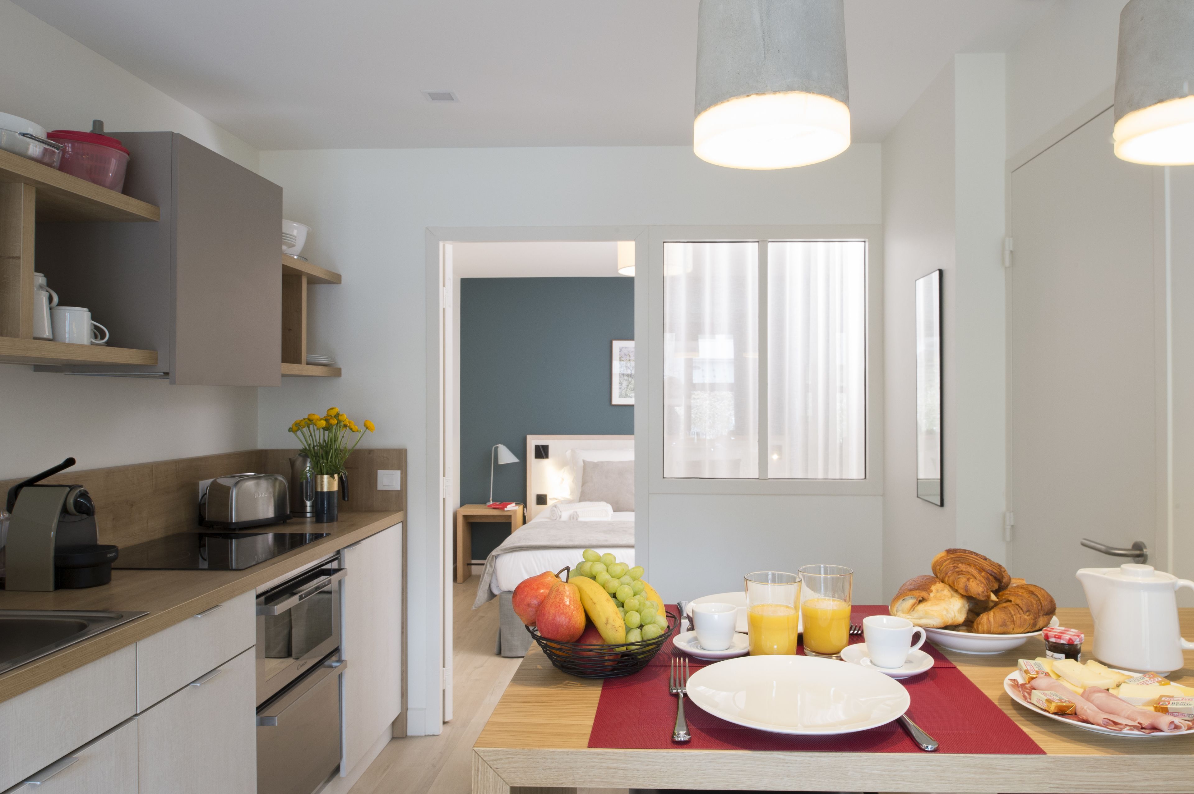 Une cuisine moderne équipée d’un coin petit-déjeuner avec des fruits, des viennoiseries et une cafetière.