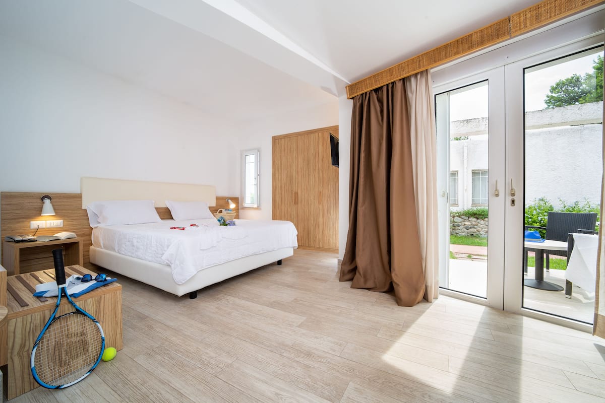 Une chambre d’hôtel avec un lit, une table de chevet, une lampe et une vue sur l’extérieur.