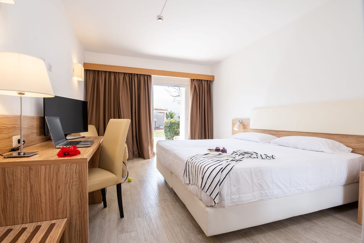 Une chambre d’hôtel équipée d’un lit, d’un bureau, d’une chaise et d’un ordinateur portable.