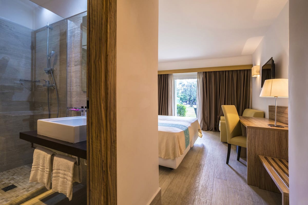 Une chambre d’hôtel avec une salle de bain, un lit, un bureau et une chaise.