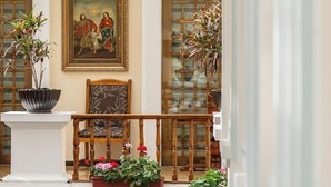 A balcony with a wooden railing, potted plants, and a framed painting on the wall. - Hotel Patio Andaluz (Quito)